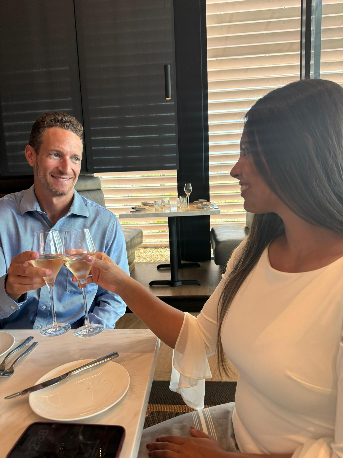 Rob and Veronica raising a glass across a restaurant table